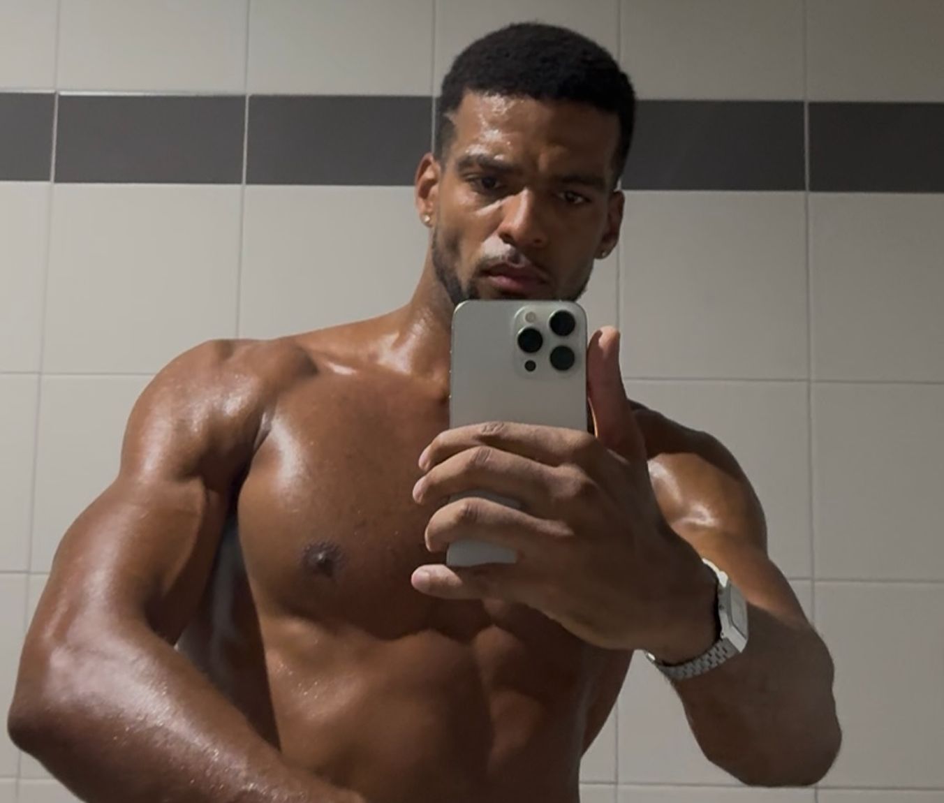 Mirror selfie of Manu today, chest, shoulders and arms well defined, phone in hand and a watch on
